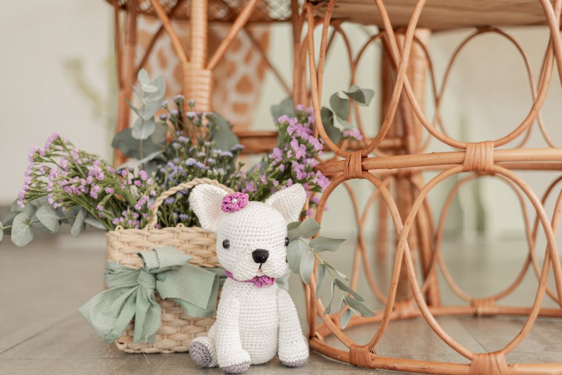 Bulldog branco de crochê, a Alba, entre flores e móveis de rattan